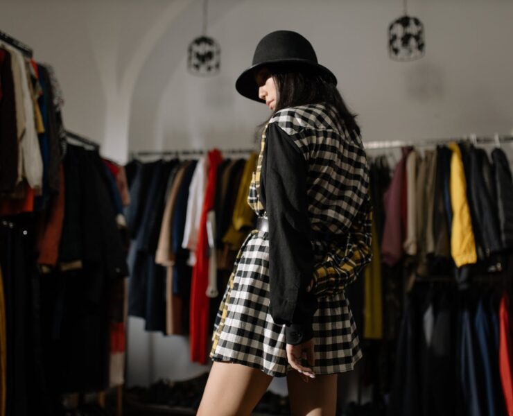 woman in black leather jacket and black hat standing near clothes rack