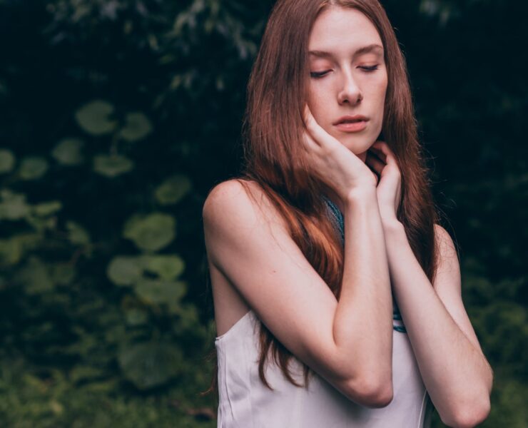 woman closing her eyes wearing white tank top
