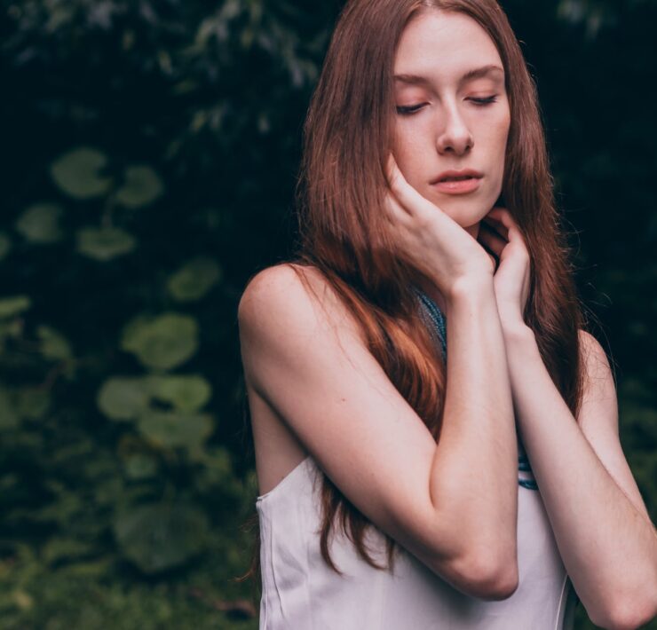 woman closing her eyes wearing white tank top