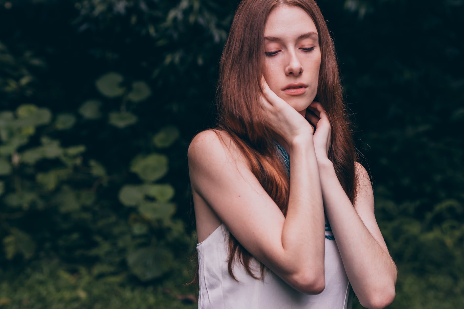woman closing her eyes wearing white tank top