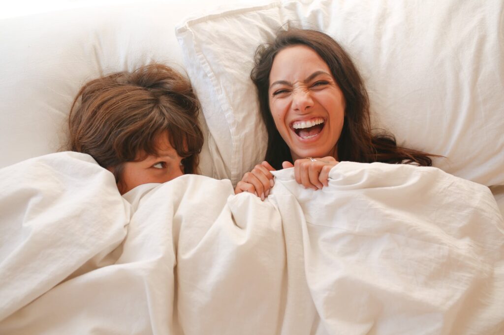 woman lying on bed covered with white blanket