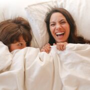 woman lying on bed covered with white blanket