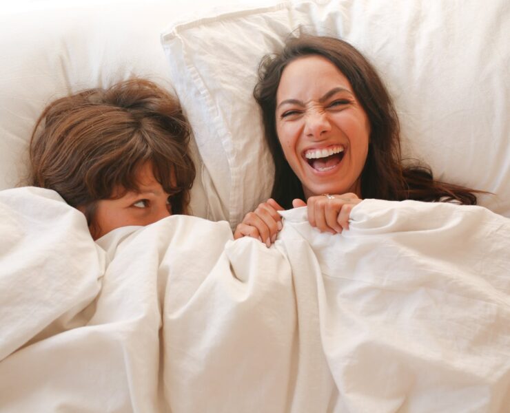 woman lying on bed covered with white blanket