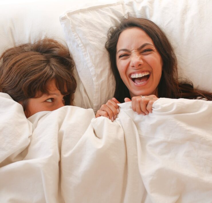 woman lying on bed covered with white blanket