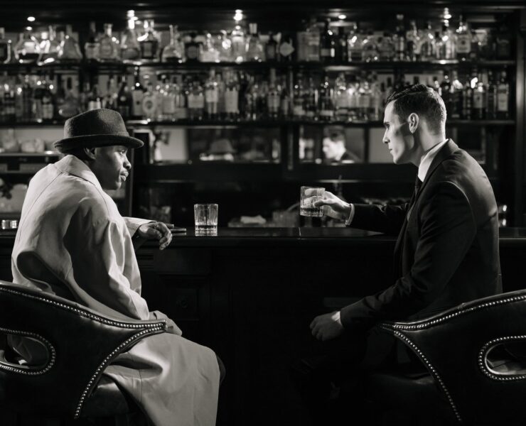 monochrome photo of men sitting in front of bar counter