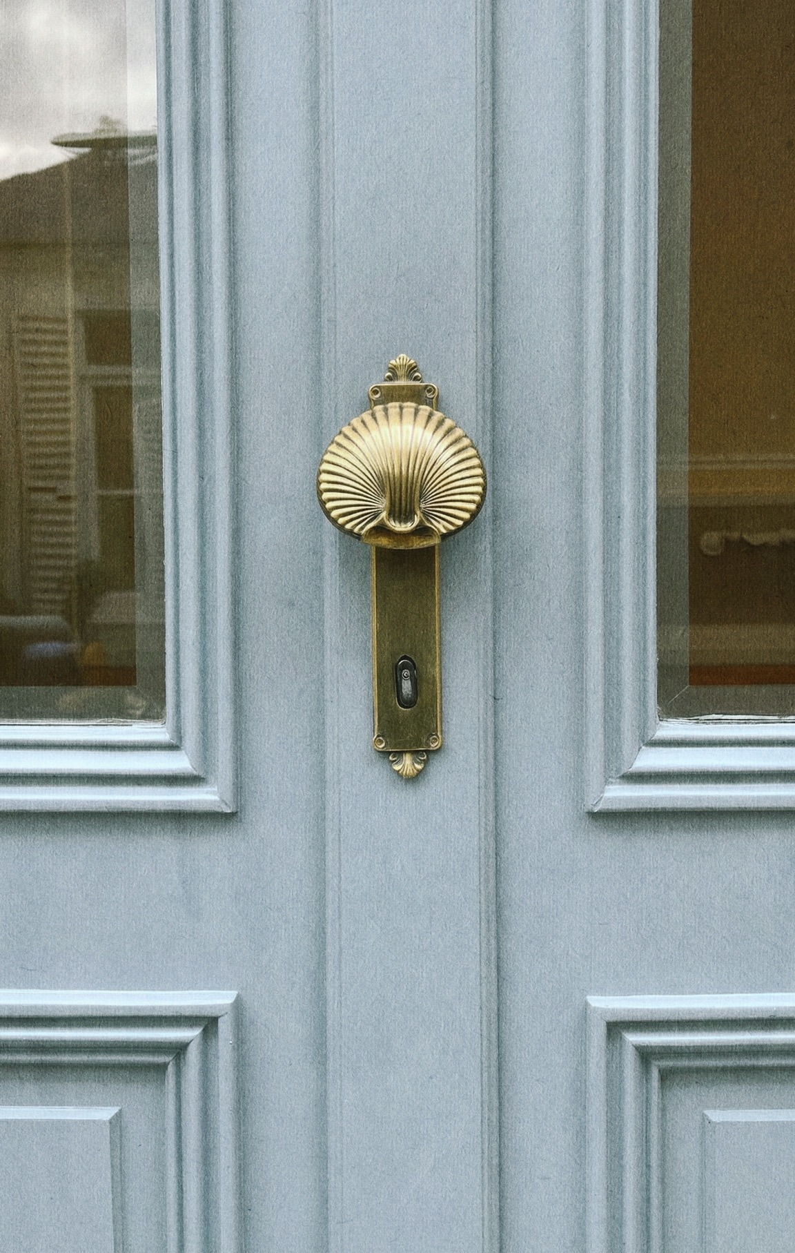 Brass door hardware on a pale blue paneled door, Neo Deco bathroom detail